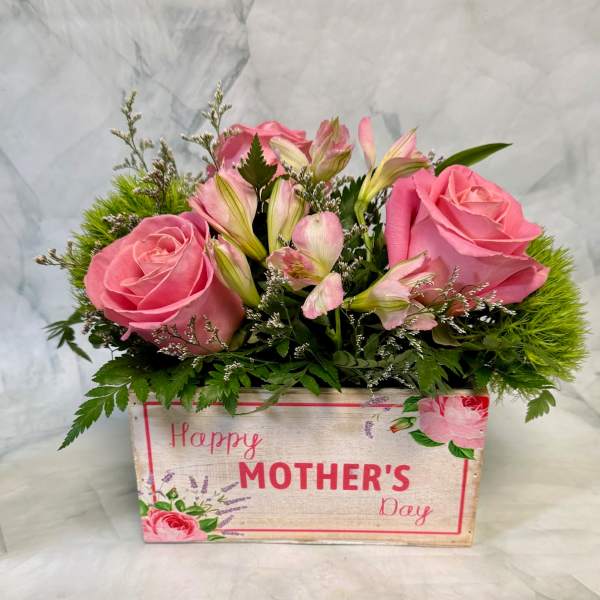 Low box arrangement of pink roses and alstroemeria with green accents in a Happy Mother's Day container.