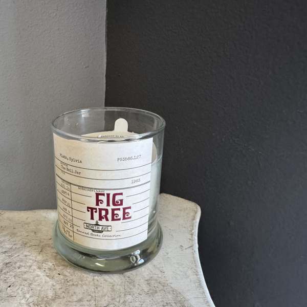A glass candle jar with a Fig Tree label sits on a small table.