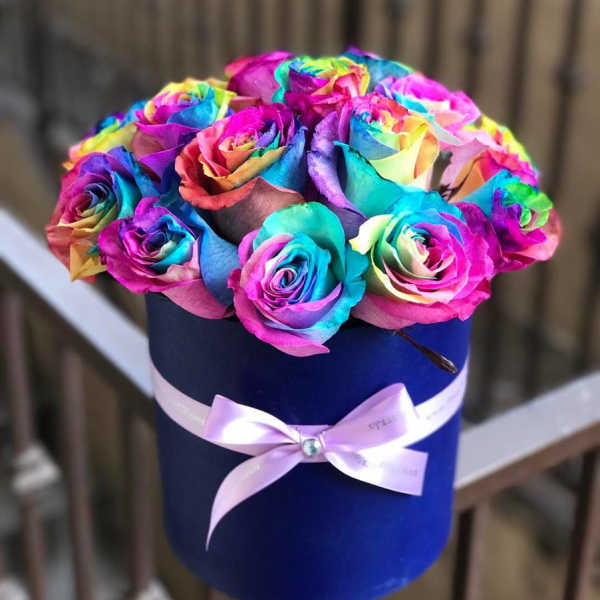 Rainbow-colored roses in a blue hatbox with a pink ribbon