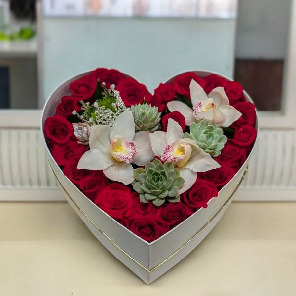 Heart-shaped box with red roses, white orchids, and succulents arranged tightly together