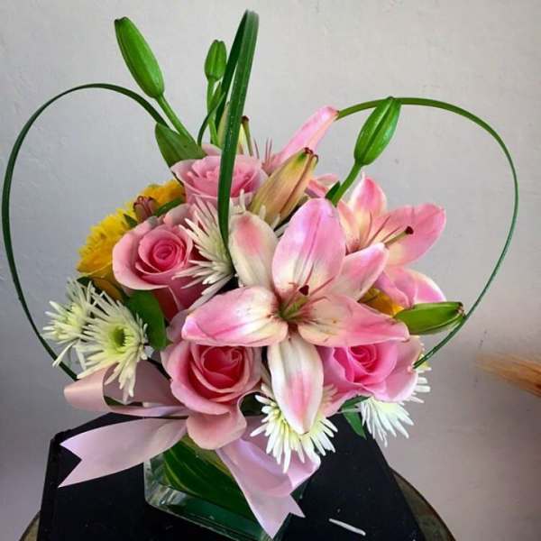 Pink lilies and roses arranged with white daisies in a vase