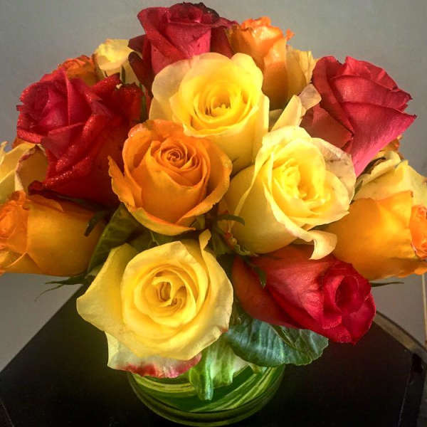 Bouquet of red, yellow, and orange roses in a glass vase