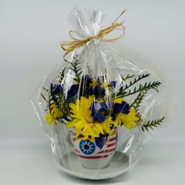 Yellow and blue flowers in a patriotic ceramic pot wrapped in plastic