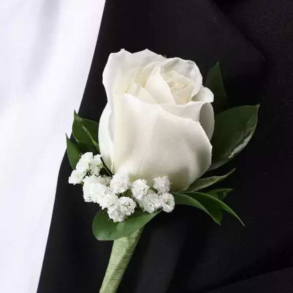 White rose boutonniere with small white filler flowers on a black suit lapel