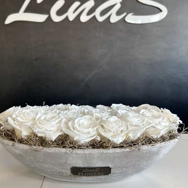 White roses arranged in a shallow gray bowl with dried filler