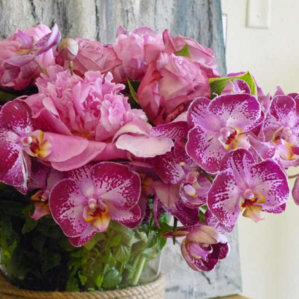 Pink orchids and roses arranged in a glass vase