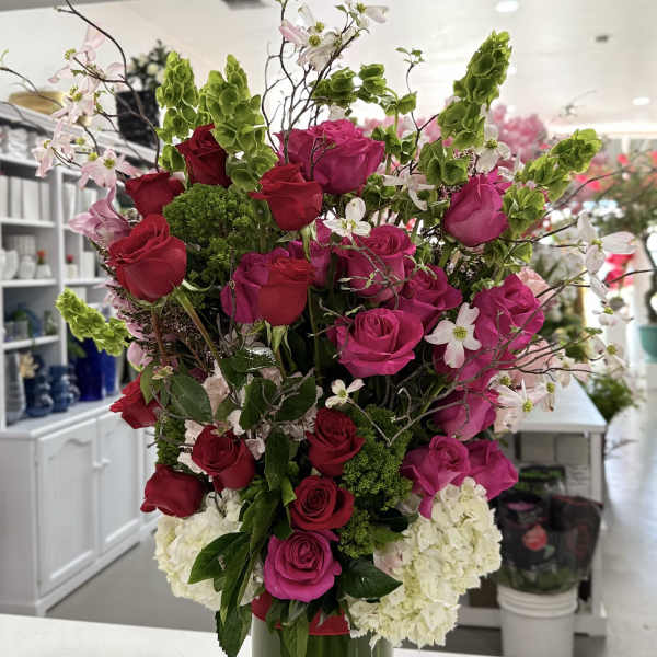 Tall bouquet of pink and red roses in a green glass vase