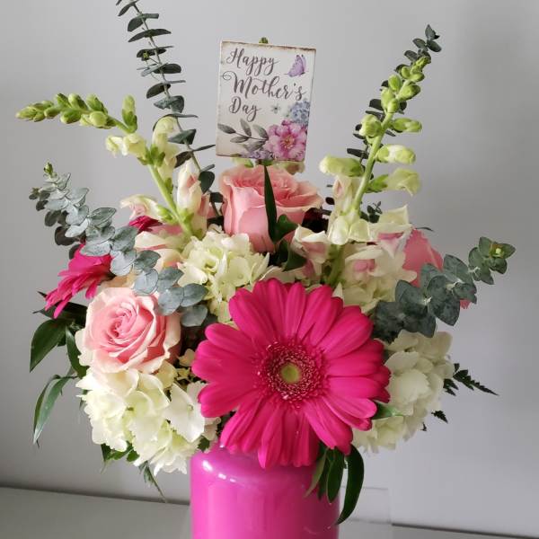 Pink and white floral arrangement in a bright pink vase with a Mother’s Day card