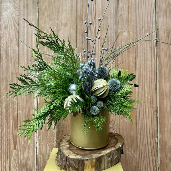 Green holiday arrangement in a gold container with tall berry stems