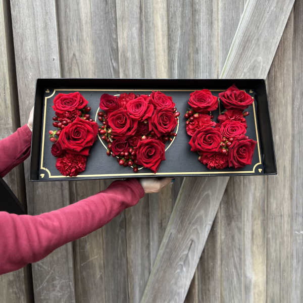 Red roses arranged in a black rectangular gift box