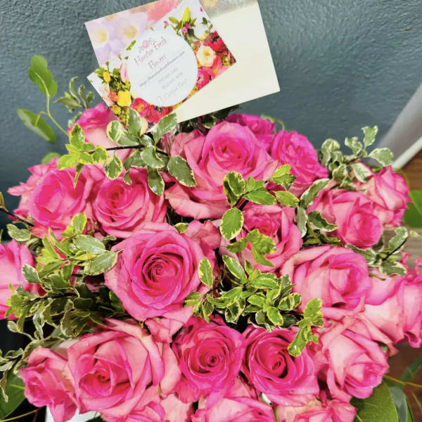 Bouquet of bright pink roses with variegated greenery