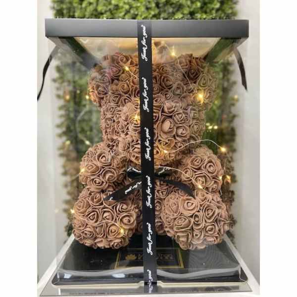 Teddy bear made of peach artificial roses in a clear gift box with ribbon and string lights