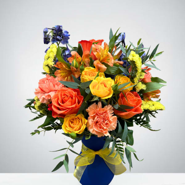 Colorful bouquet of roses, carnations, and alstroemeria in a blue vase