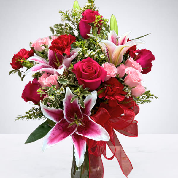 Bouquet of pink and red roses with lilies in a glass vase