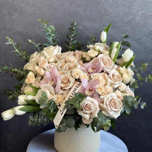 Cream rose and pink orchid arrangement in a white vase