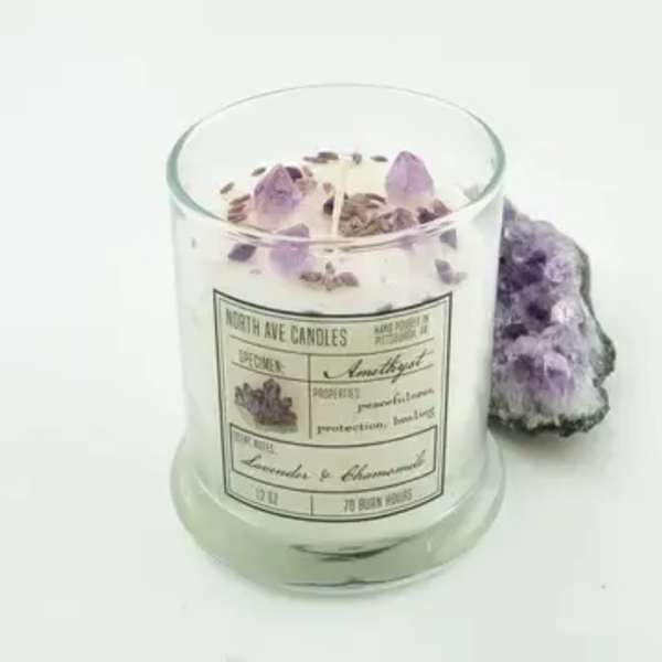 Lavender-scented candle in a glass jar with purple crystals beside it