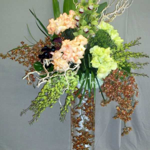 Tall floral arrangement in a clear glass vase with peach and green blooms