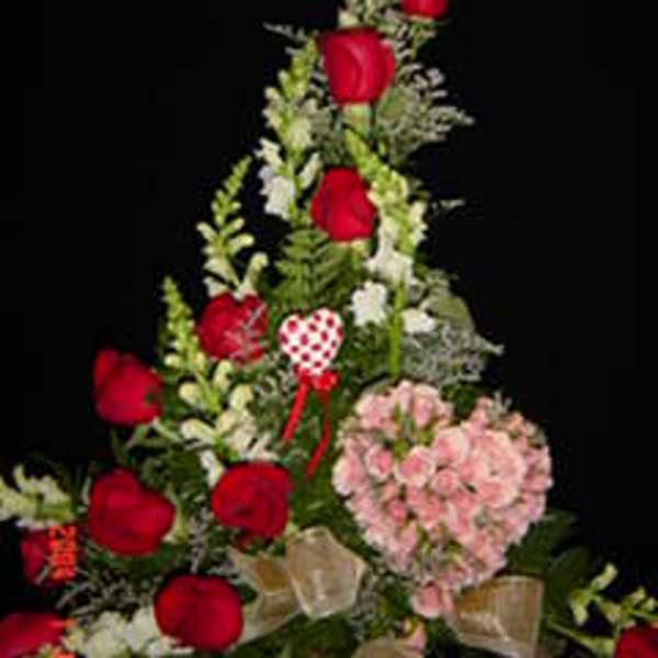 Tall floral arrangement with red roses and pink blooms on a black background