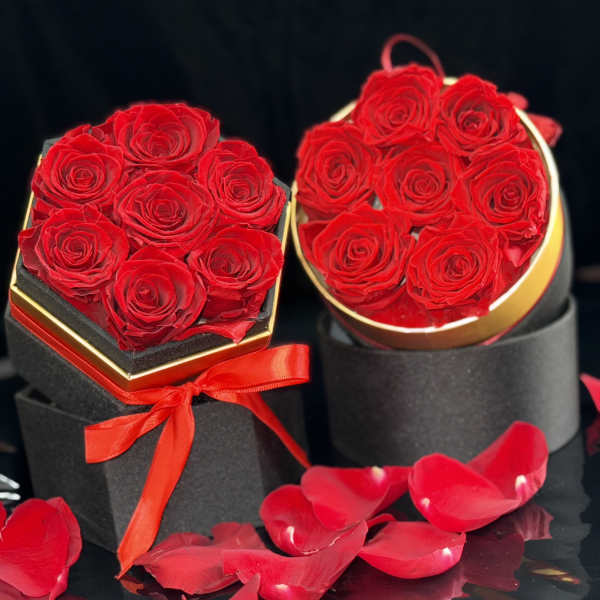 Two black hat boxes filled with red roses and rose petals
