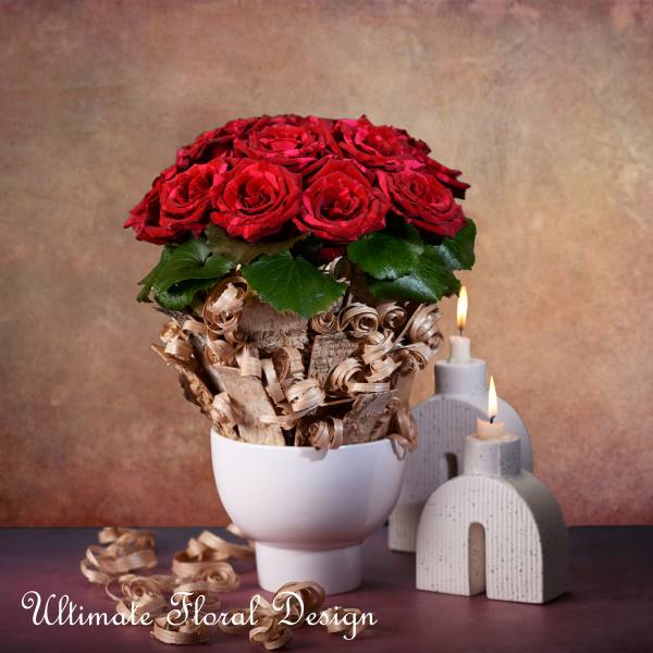 Red rose bouquet in a white vase with decorative wood curls