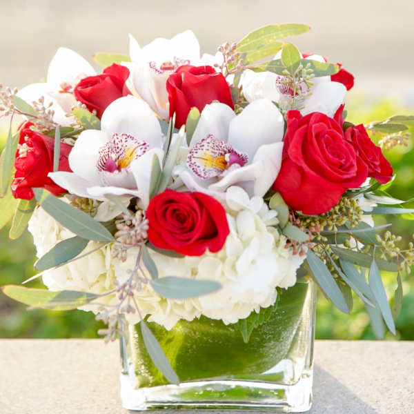 Red roses and white orchids arranged in a clear glass vase