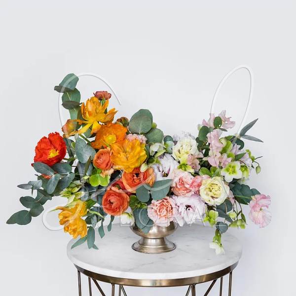 Colorful floral arrangement in a metal vase on a round table