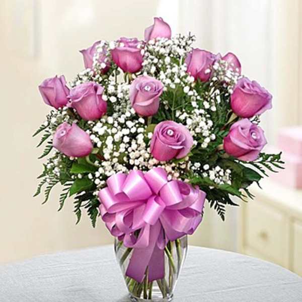 Pink roses in a clear vase with a lavender ribbon