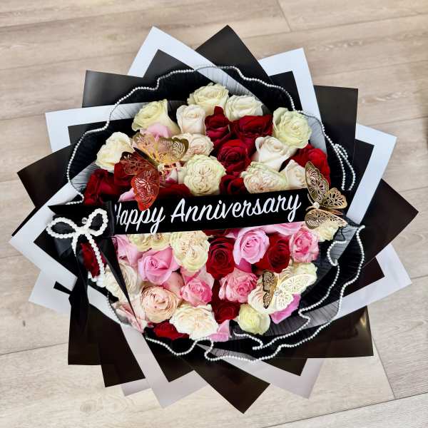 Bouquet of red, pink, and white roses with a Happy Anniversary sign