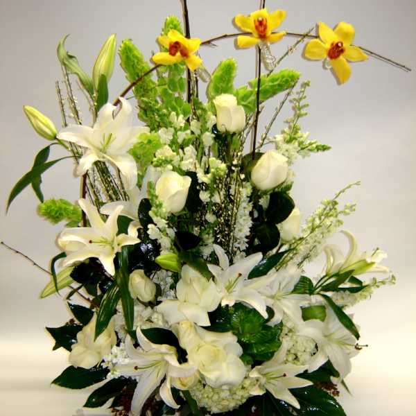 White lilies and roses with yellow orchids in a tall arrangement