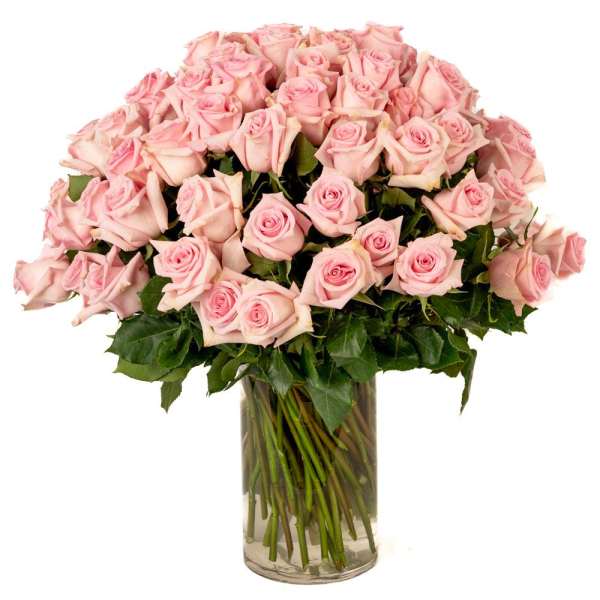 Large arrangement of light pink roses in a clear glass cylinder vase