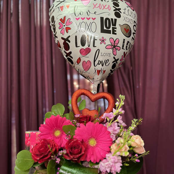 Heart-shaped balloon above a pink flower arrangement in a vase
