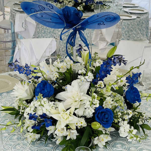 Blue and white floral centerpieces with butterfly decorations on round tables