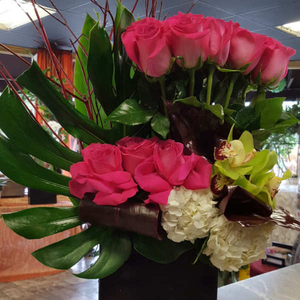 Pink roses and orchids arranged in a tall black vase