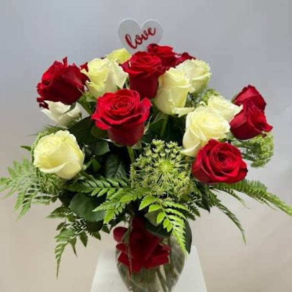 Red and white roses in a glass vase with a heart "love" pick