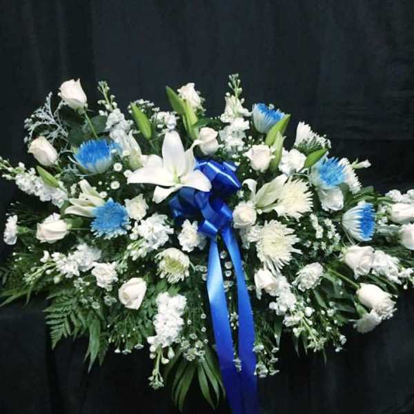 White floral spray with blue accents and a blue ribbon on a black background