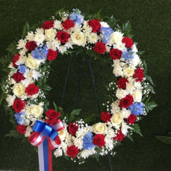 Circular floral wreath with red, white, and blue flowers on a stand
