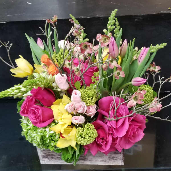 Mixed bouquet in a rectangular wooden box with pink, yellow, and green flowers
