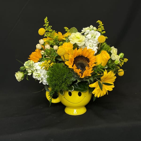 Yellow flower arrangement in a smiley-face mug