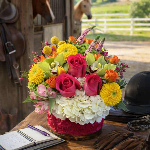 Colorful mixed flower arrangement in a round box on a wooden table