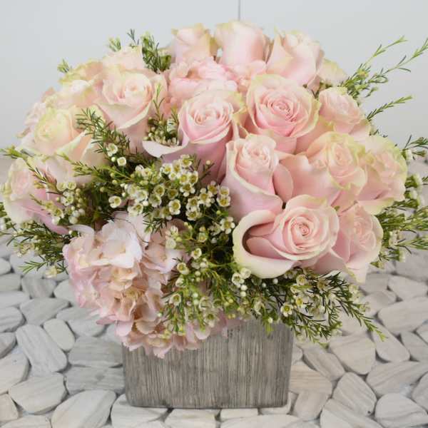 Pink roses and pale hydrangea in a square wooden vase