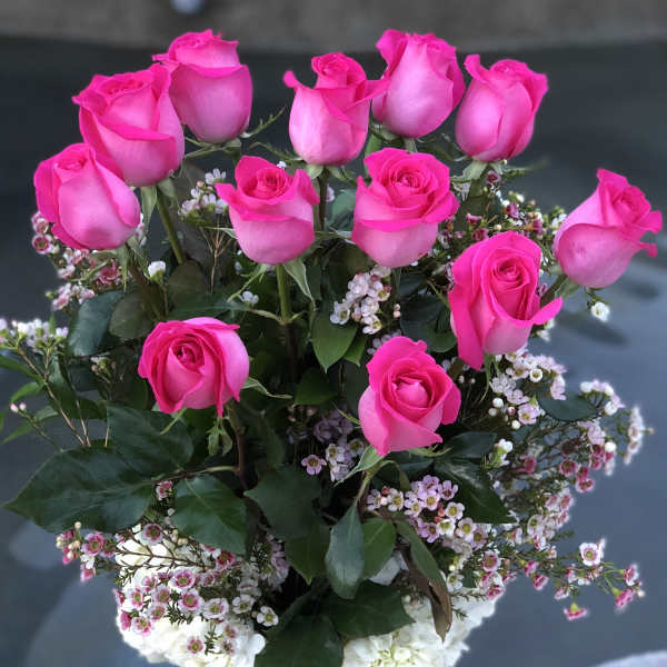Pink roses arranged in a clear glass vase with white filler flowers