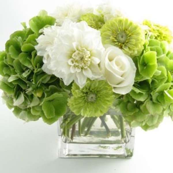 Green and white bouquet in a clear square vase