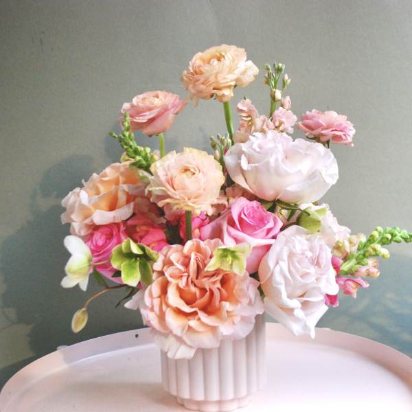 Pink and peach roses arranged in a white vase