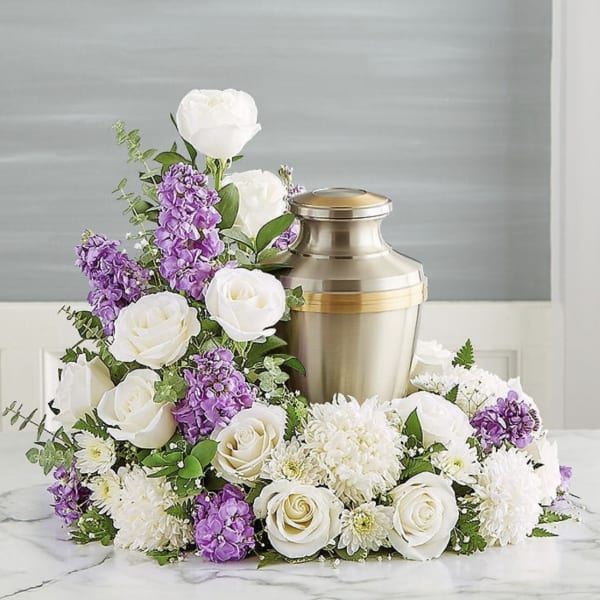 White and purple floral arrangement around a metal urn