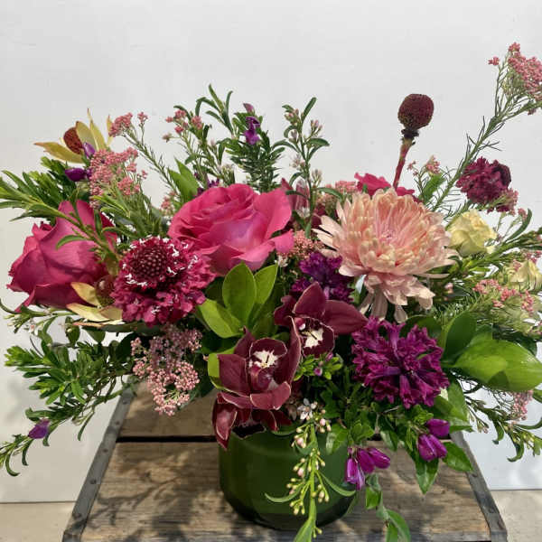 Mixed pink and purple floral arrangement in a green vase