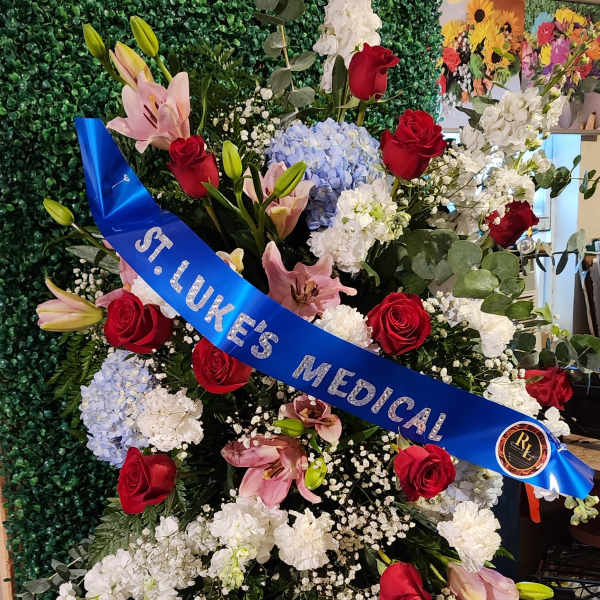 Standing funeral spray with red roses, pink lilies, and white flowers