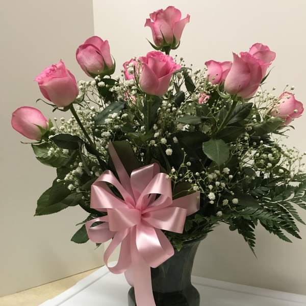 Pink roses in a dark vase with a pink ribbon bow