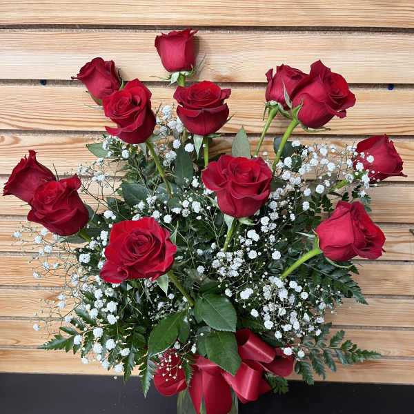 Red roses arranged in a glass vase with white baby's breath