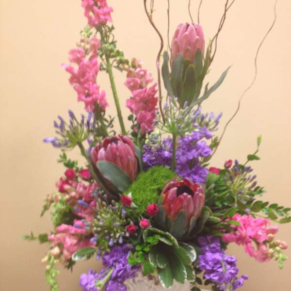 Tall mixed bouquet with pink and purple flowers in a white vase