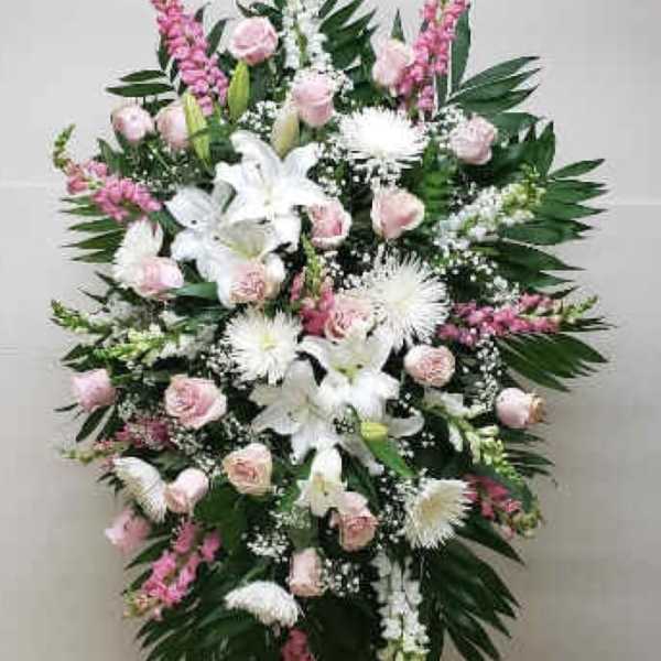 Tall standing spray of white lilies and mums with pink roses on a metal easel
